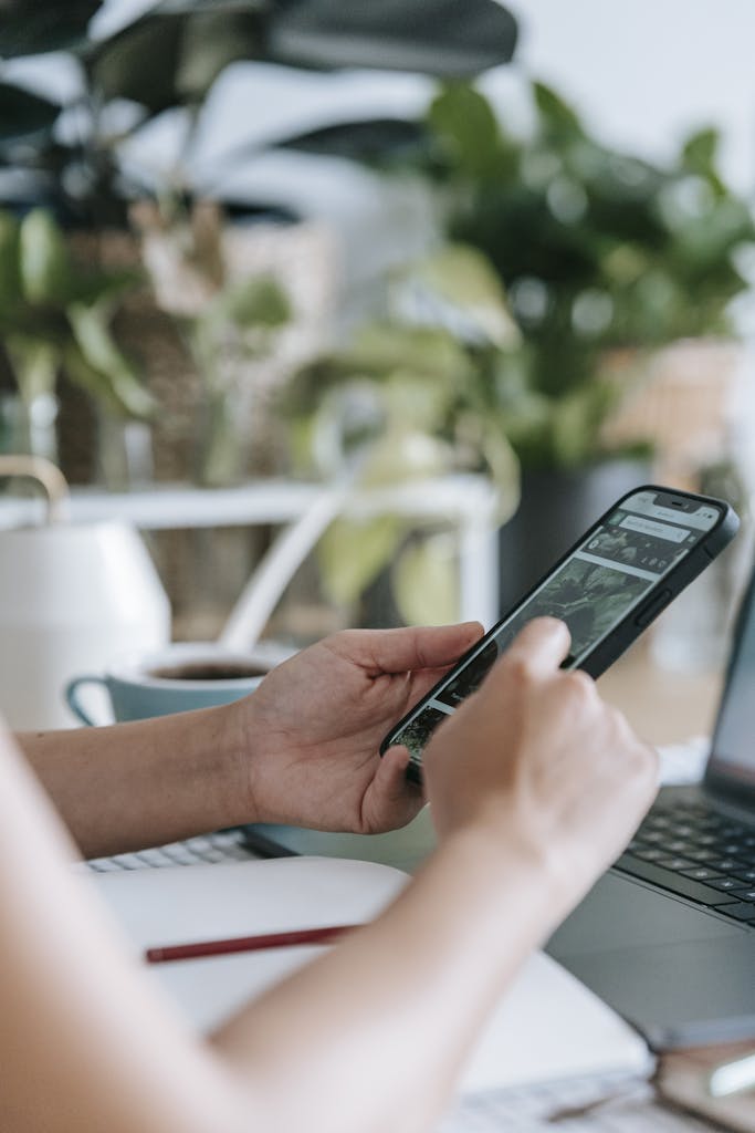 Unrecognizable person browsing smartphone in room with houseplants